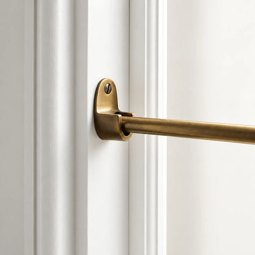 A close-up of a brass door rod mounted on a white paneled door frame.